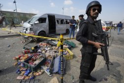 ضابط شرطة باكستاني يقف للحراسة بينما يفحص المحققون موقع هجوم انتحاري في كراتشي الجمعة (أ.ب)